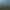 Un terrain de golf verdoyant entouré d'une forêt dense avec un bâtiment au sommet d'une colline et une vue sur l'océan au loin